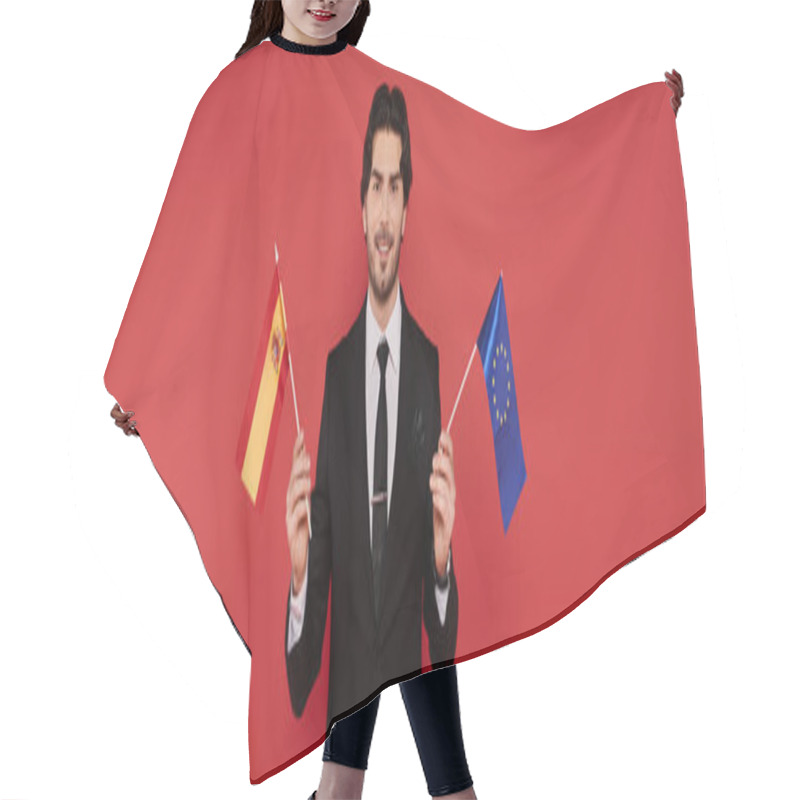 Personality  A Young Man Smiles While Holding The Flags Of Spain And The EU. Hair Cutting Cape