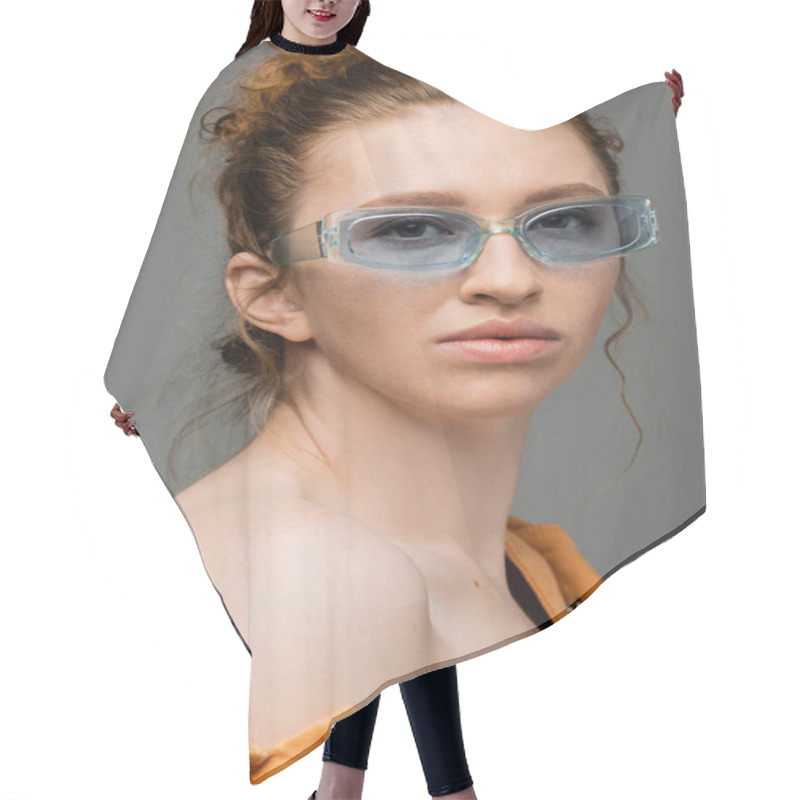 Personality  Portrait Of Redhead And Freckled Woman In Sunglasses And Orange Denim Jacket With Naked Shoulder Looking At Camera Isolated On Grey Background, Trendy Sun Protection Concept, Fashion Model  Hair Cutting Cape