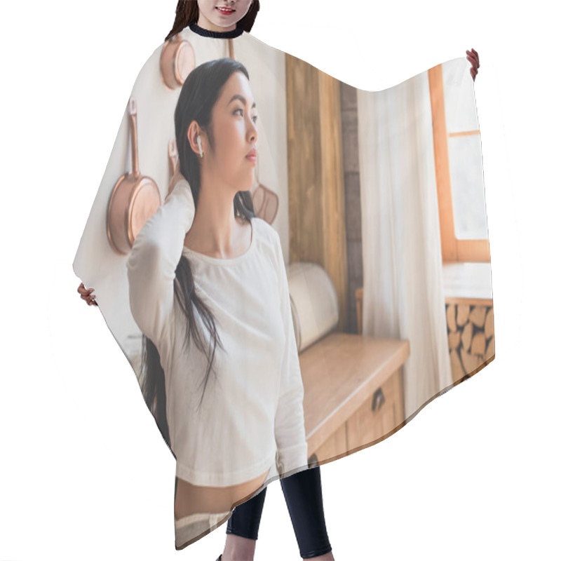 Personality  Tired Young Asian Woman In White Blouse Standing With Earphones And Holding Hand Near Neck In Kitchen Hair Cutting Cape