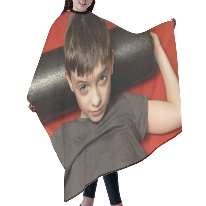 Personality  A Young Boy In A Gray T-shirt Lies On A Red Mat Using A Black Foam Roller For Back Massage. Concept Of Relaxation, Fitness, Stretching, And Muscle Recovery. Hair Cutting Cape