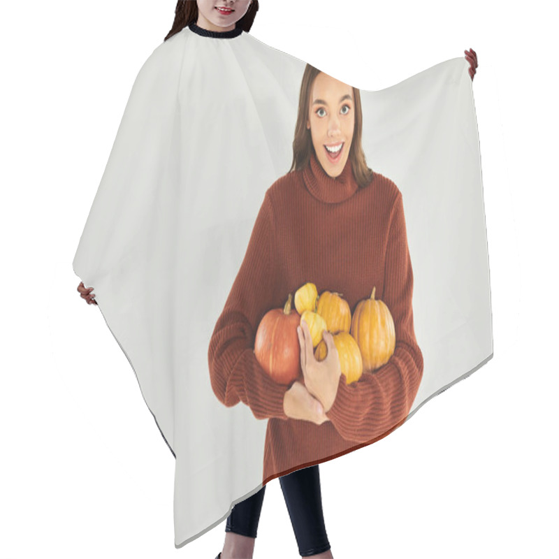 Personality  A Young Woman In A Comfy Sweater Joyfully Holds Pumpkins, Embracing Halloween Vibes. Hair Cutting Cape