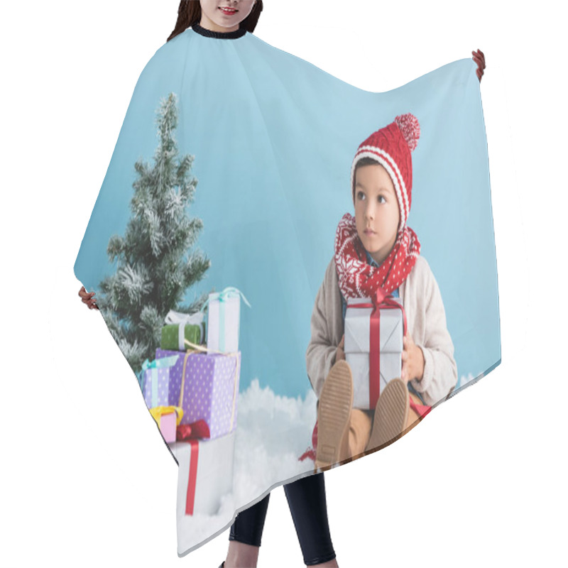 Personality  Boy In Hat And Winter Outfit Sitting On Snow Near Presents And Christmas Trees Isolated On Blue Hair Cutting Cape