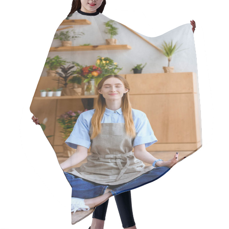 Personality  Smiling Young Florist In Apron Sitting In Lotus Position On Floor In Flower Shop Hair Cutting Cape