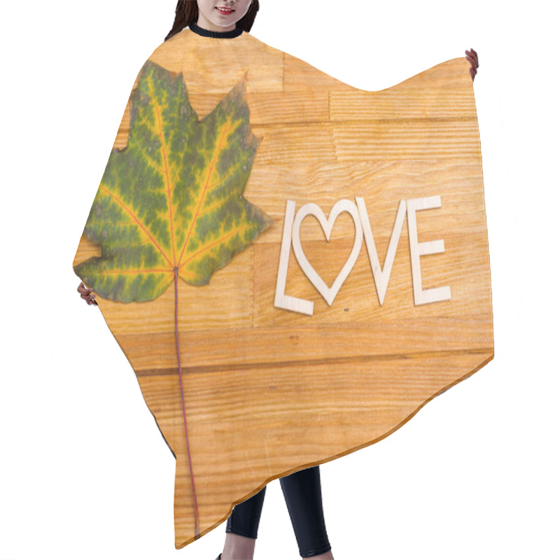 Personality  Wooden Inscription LOVE On An Autumn Leaf On A Wooden Rural Table. Shot From Above. Hair Cutting Cape