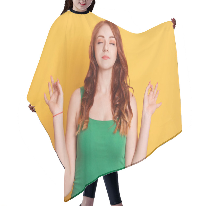 Personality  Red Haired Peaceful Caucasian Woman In Green T Shirt Meditates Indoor Against Yellow Wall, Keeps Hands In Mudra Gesture, Has Eyes Closed, Relaxes After Long Hours Working, Holds Fingers In Yoga Sign Hair Cutting Cape