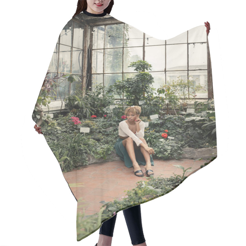 Personality  Young And Trendy African American Woman In Summer Outfit Sitting Near Plants With Blooming Flowers At Background In Indoor Garden, Fashion-forward Lady In Midst Of Tropical Greenery Hair Cutting Cape