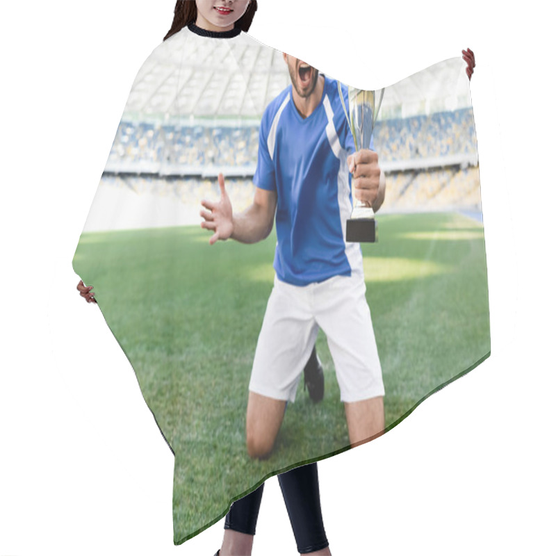 Personality  Professional Soccer Player In Blue And White Uniform With Sports Cup Standing On Knees On Football Pitch And Shouting At Stadium Hair Cutting Cape