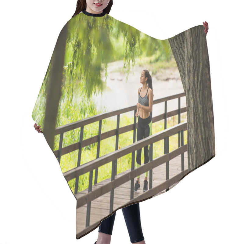 Personality  Full Length Of Happy Sportswoman In Crop Top And Leggings Jogging On Bridge Near Lake In Park  Hair Cutting Cape