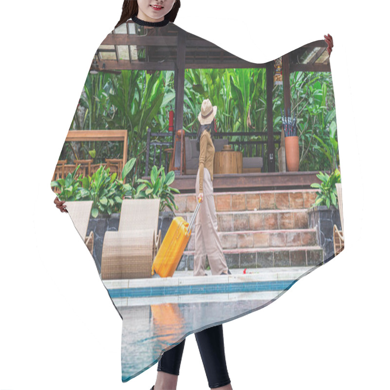 Personality  A Woman Walking By A Poolside With An Orange Suitcase, Wearing A Hat And Stylish Outfit. The Background Features Lush Greenery And A Wooden Structure, Creating A Tropical Vacation Vibe. Hair Cutting Cape