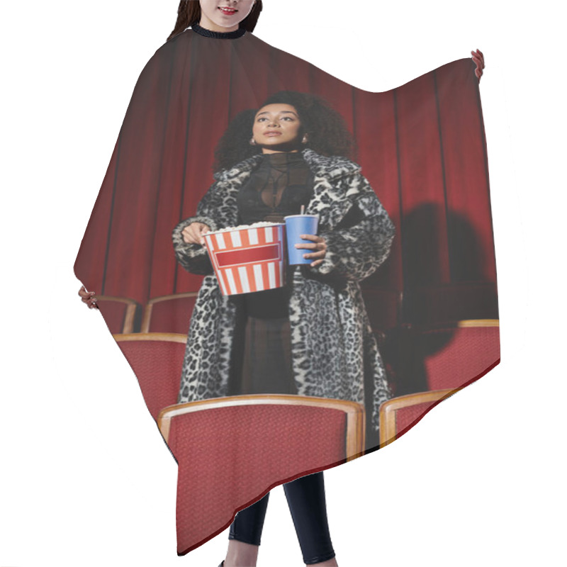 Personality  Stylish African American Woman In Leopard-print Reacts To Movie In Dark Cinema, Holding Popcorn And A Drink. Hair Cutting Cape