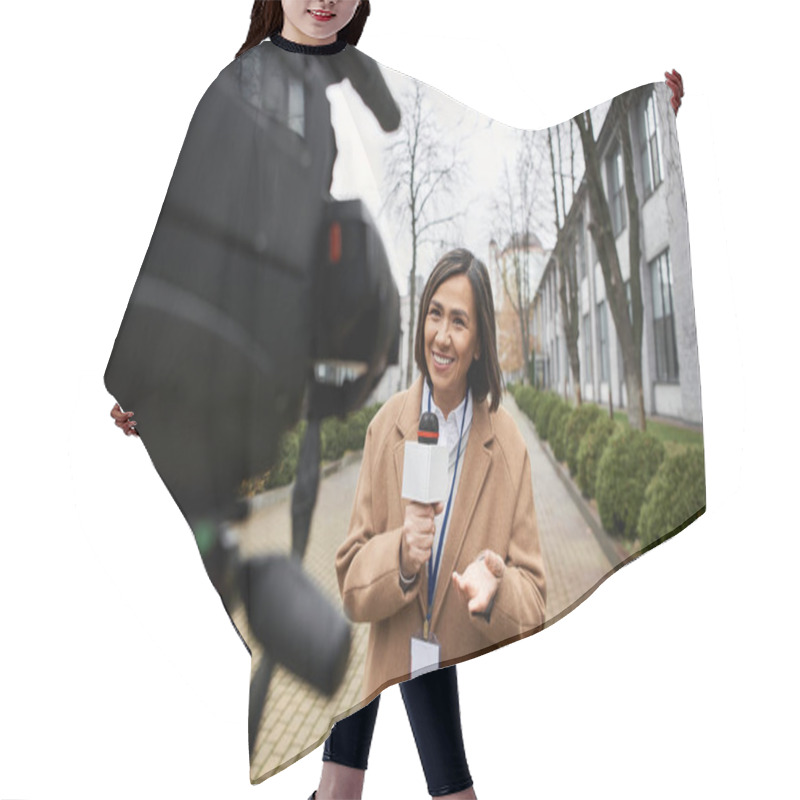 Personality  A Multiracial Female Journalist Holds A Microphone, Sharing Lively News Updates Outdoors In An Urban Setting. Hair Cutting Cape