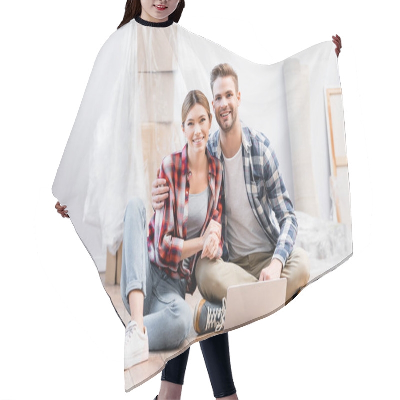 Personality  Happy Young Couple Looking At Camera While Hugging On Floor Near Laptop On Blurred Background At Home Hair Cutting Cape