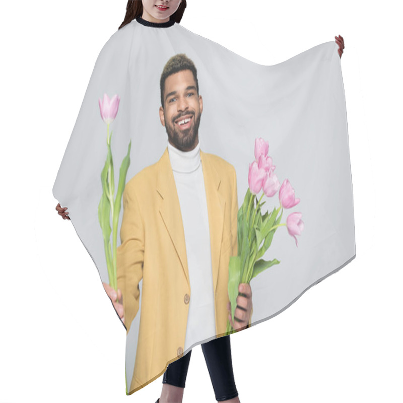 Personality  Joyful African American Man In Stylish Outfit Holding Bouquet Of Pink Tulips Isolated On Grey  Hair Cutting Cape