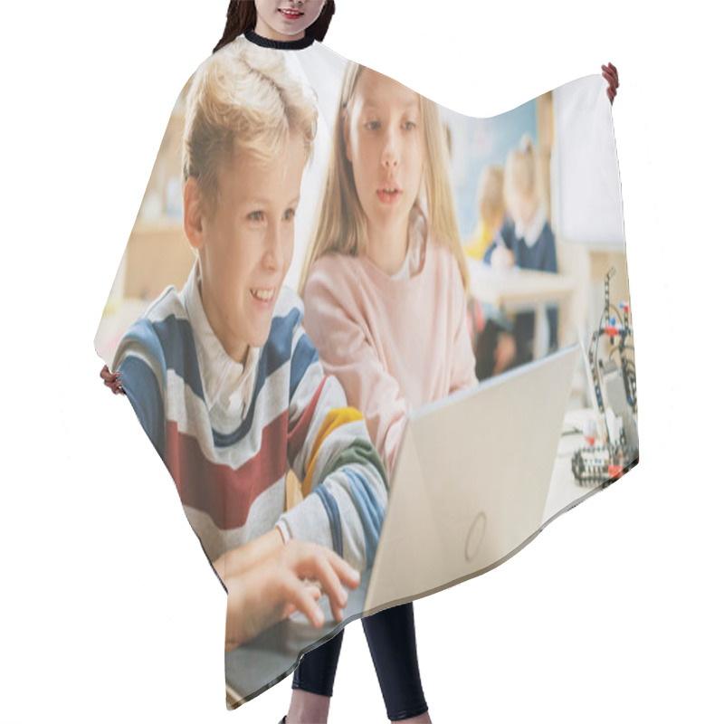 Personality  Brilliant Schoolgirl And Schoolboy Talk And Use Laptop To Program Software For Robotics Engineering Class. Elementary School Science Classroom With Children Working On Technology. STEM Education Hair Cutting Cape