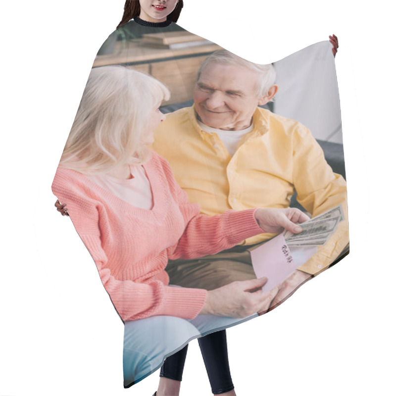 Personality  Smiling Senior Couple Holding Envelope With 'roth Ira' Lettering And Dollar Banknotes Hair Cutting Cape