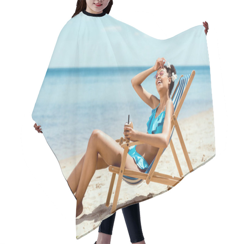 Personality  Young African American Woman In Bikini Wiping Forehead And Holding Cocktail In Coconut Shell While Laying On Deck Chair On Sandy Beach  Hair Cutting Cape