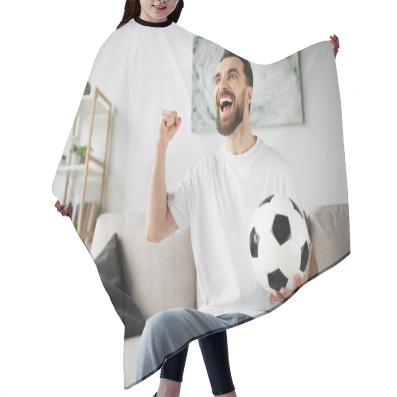 Personality  Excited Football Fan Holding Ball And Showing Triumph Gesture While Watching Match In Living Room At Home Hair Cutting Cape