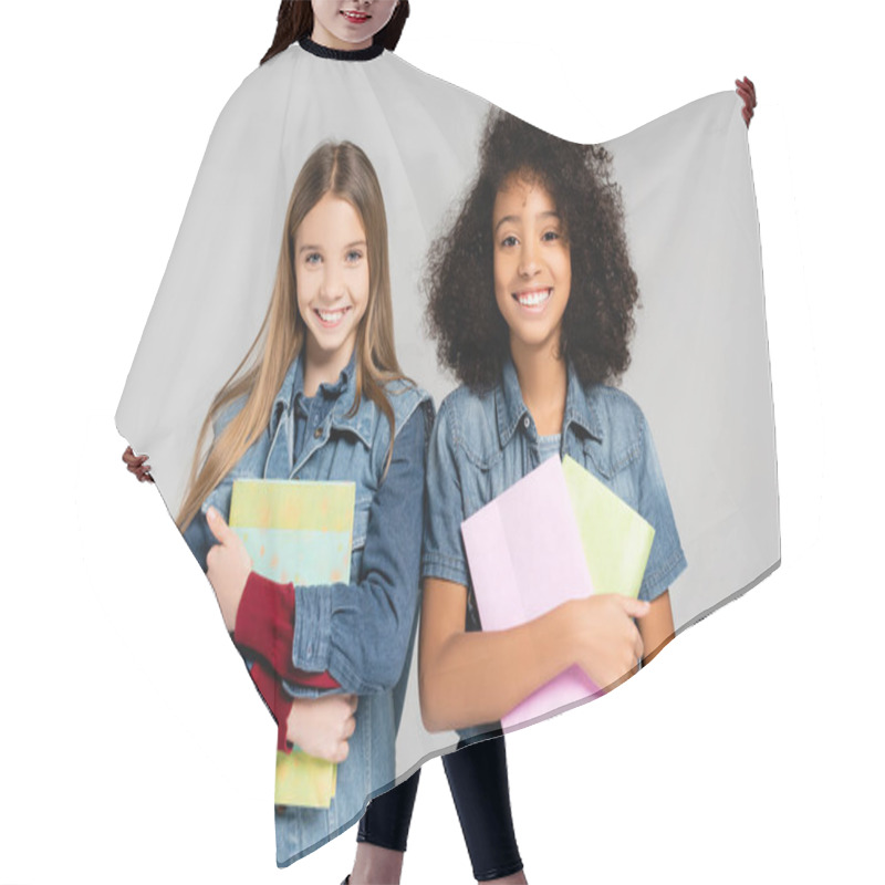 Personality  Joyful, Trendy Interracial Schoolgirls Holding Books And Smiling At Camera Isolated On Grey Hair Cutting Cape