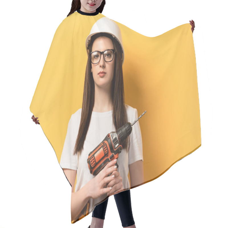 Personality  Serious Handywoman Holding Drill And Looking At Camera On Yellow Background  Hair Cutting Cape