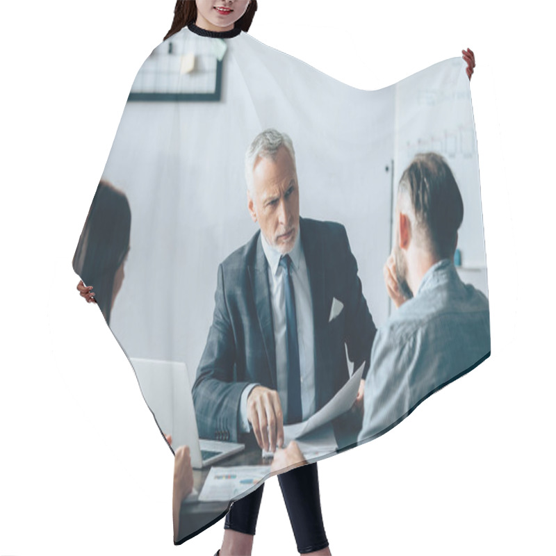 Personality  Mature Investor Holding Document And Looking At Business Partners On Blurred Foreground During Consulting In Office  Hair Cutting Cape