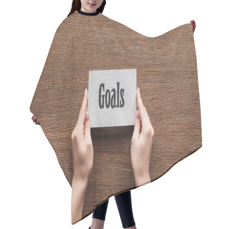 Personality  Cropped View Of Woman Holding Card With 'goals' Lettering In Hands On Wooden Background Hair Cutting Cape