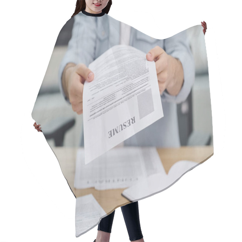 Personality  A Job Seeker Holds Up A Paper At A Desk. Hair Cutting Cape