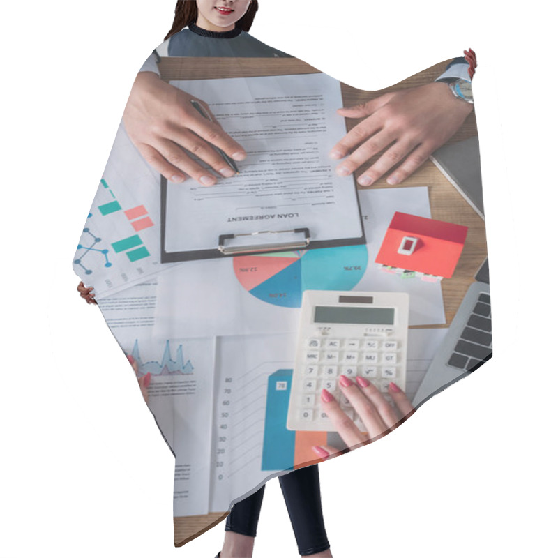 Personality  Partial View Of Customer Reading Loan Agreement And Businesswoman Using Calculator While Sitting At Workplace Near Laptop, House Model, Graphs And Charts Hair Cutting Cape