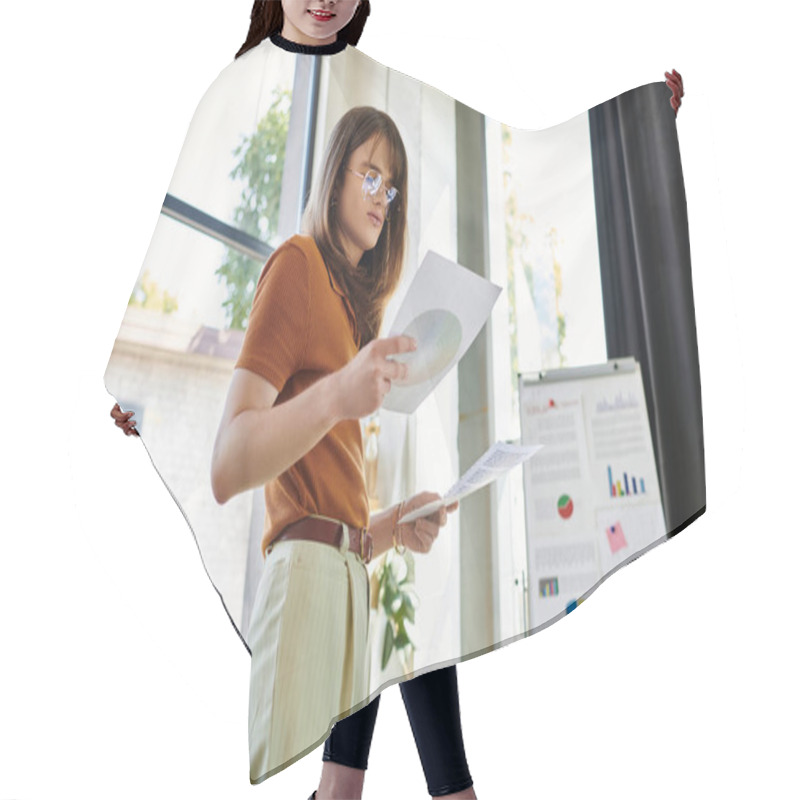 Personality  Focused Individual Examines Printed Materials While Standing In A Bright Office Space. Hair Cutting Cape