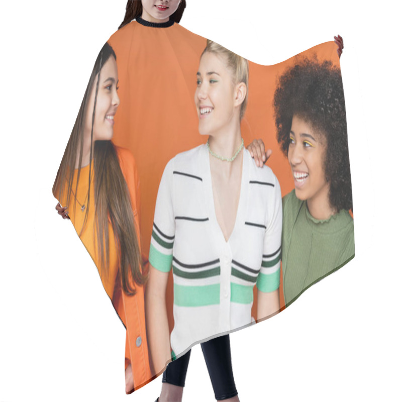 Personality  Portrait Of Positive And Multiethnic Teenage Girlfriends In Trendy Outfits With Makeup Talking And Looking At Each Other On Orange Background, Cultural Diversity And Generation Z Fashion Concept Hair Cutting Cape