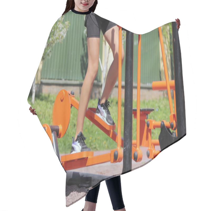 Personality  Outdoor Fitness Equipment In Use At Park. A Person Using Vibrant Orange Outdoor Fitness Equipment In A Park, Exercising On A Sunny Day With A Green Background Hair Cutting Cape