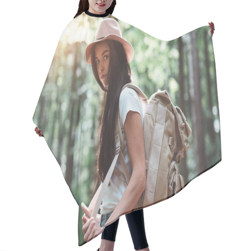 Personality  Handsome Traveler Woman With Backpack And Hat Standing In Forest. Young Hipster Girl Walking Among Trees On Sunset Hair Cutting Cape