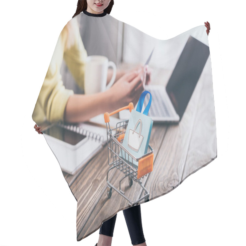 Personality  Selective Focus Of Small Shopping Bag In Shopping Trolley With Woman Using Laptop On Background Hair Cutting Cape