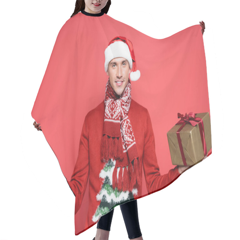 Personality  Smiling Man In Santa Hat Holding Gift Boxes And Looking At Camera On Red Background Hair Cutting Cape