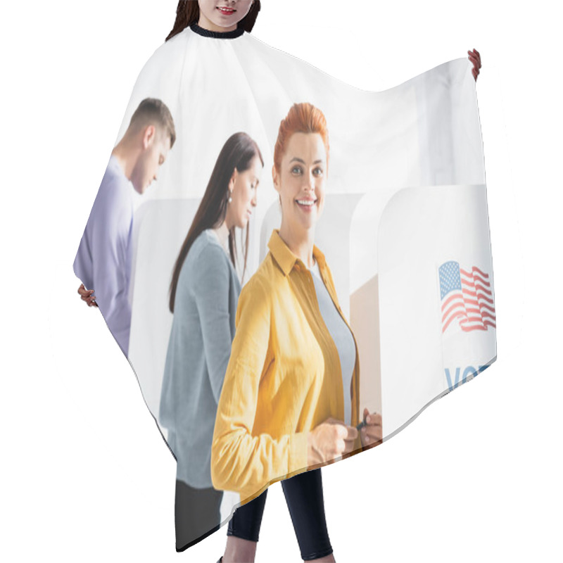 Personality  Woman Smiling At Camera Near Polling Booth With American Flag And Vote Lettering, And Electors On Blurred Background Hair Cutting Cape