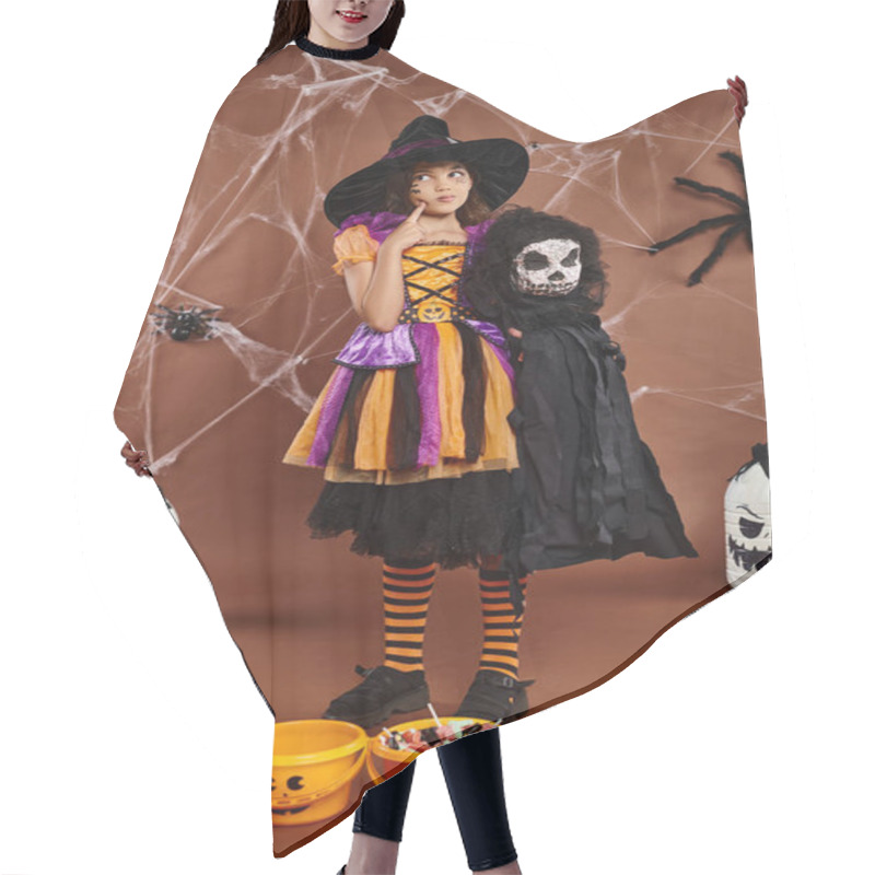 Personality  Preteen Girl In Witch Hat With Spooky Toy And Touching Her Cheek And Looks Away, Halloween Hair Cutting Cape