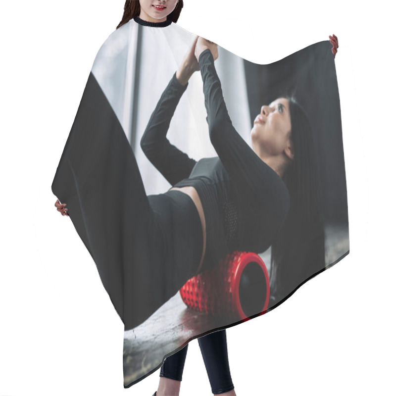 Personality  Fitness Trainer In A Black Tracksuit Lies With Her Back On A Massage Roll With Hands Above Him And Works Through The Fascia Of The Spinal Muscles. Hair Cutting Cape