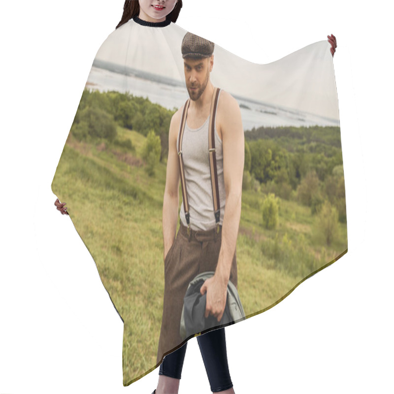 Personality  Stylish Bearded Man In Newsboy Cap And Suspenders Holding Hand In Pocket Of Pants And Jacket While Looking At Camera And Standing With Landscape At Background, Fashion-forward In Countryside Hair Cutting Cape