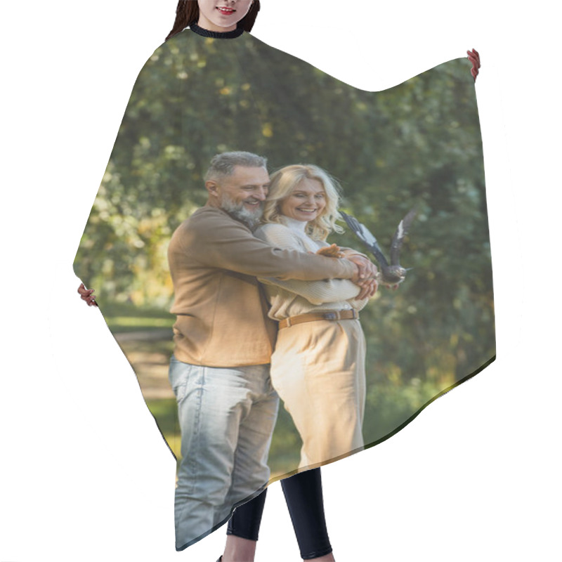 Personality  Pleased Middle Aged Man Hugging Blonde Wife Near Flying Pigeon In Park  Hair Cutting Cape