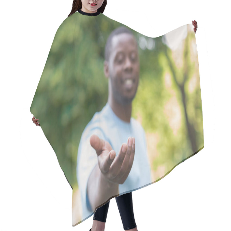 Personality  Cheerful black man reach his hand at camera hair cutting cape