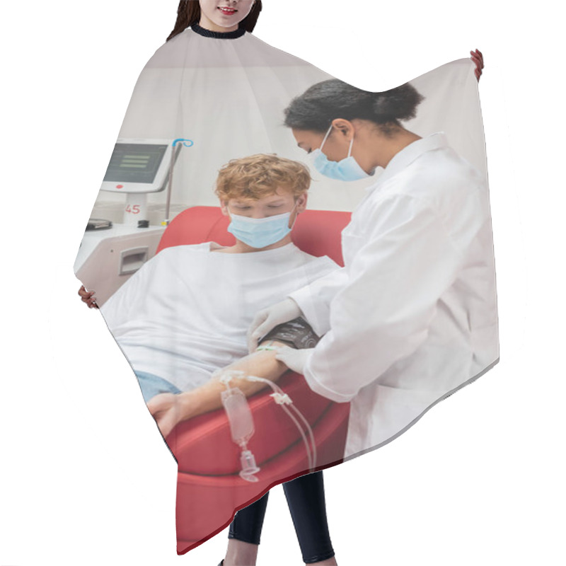 Personality  Multiracial Doctor In White Uniform And Medical Mask Sticking Band-aid On Arm Of Redhead Man With Transfusion Set Sitting On Medical Chair Near Automated Equipment In Blood Donation Center Hair Cutting Cape