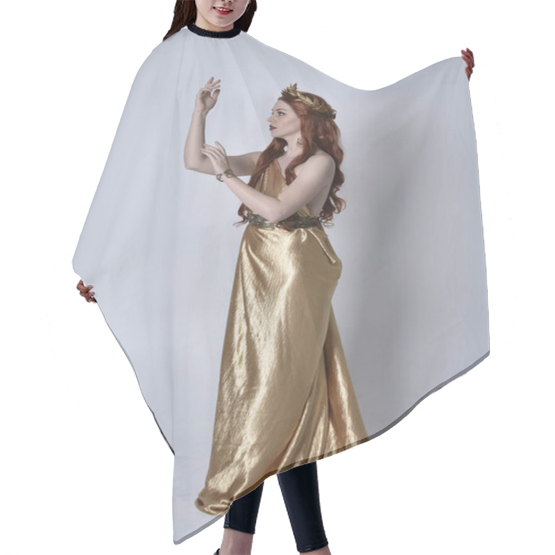 Personality  Full Length Portrait Of Girl With Red Hair Wearing Long Grecian Toga And Golden Wreath. Standing Pose In Side Profile,  Isolated Against A Grey Studio Background. Hair Cutting Cape