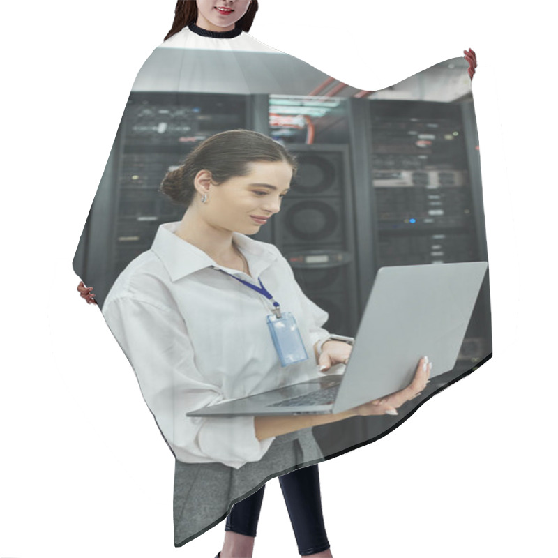 Personality  IT Specialist In A White Shirt Engages With A Laptop Among Server Hardware In A Data Center. Hair Cutting Cape