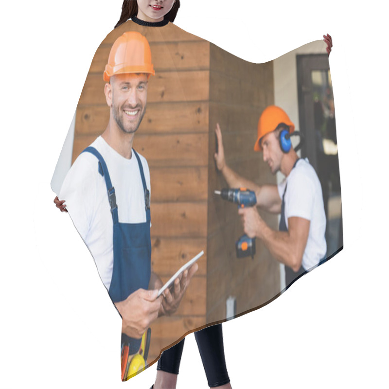 Personality  Selective Focus Of Builder Holding Digital Tablet While Colleague Using Electric Screwdriver Near Facade Of Building  Hair Cutting Cape