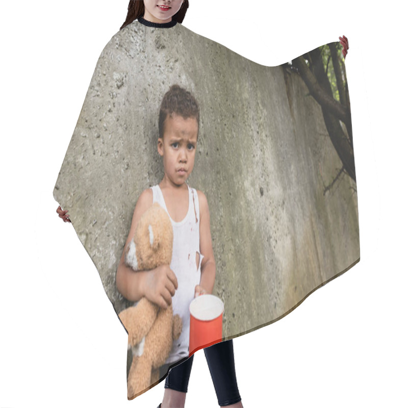 Personality  Displeased African American Boy Holding Dirty Teddy Bear And Metal Cup Near Concrete Wall On Urban Street  Hair Cutting Cape