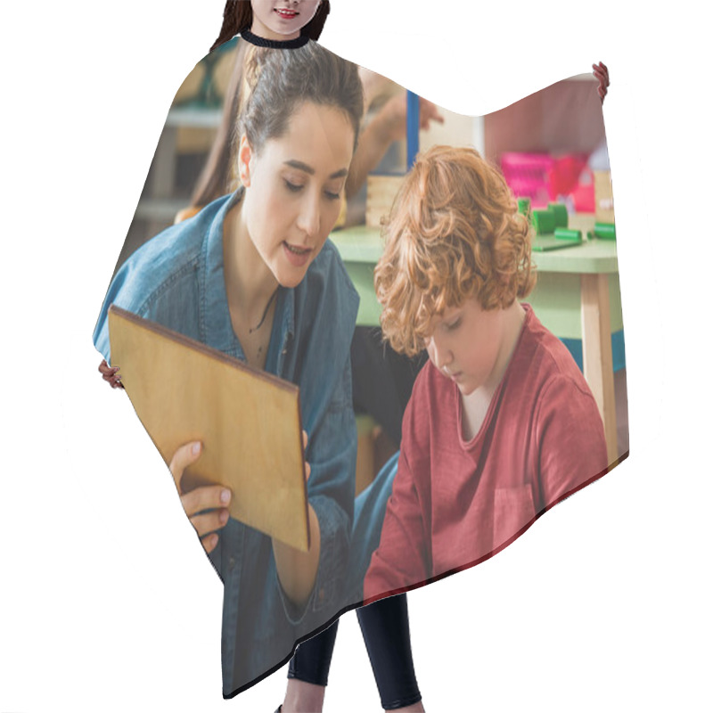 Personality  Young Teacher Showing Wooden Board To Redhead Boy During Lesson Hair Cutting Cape