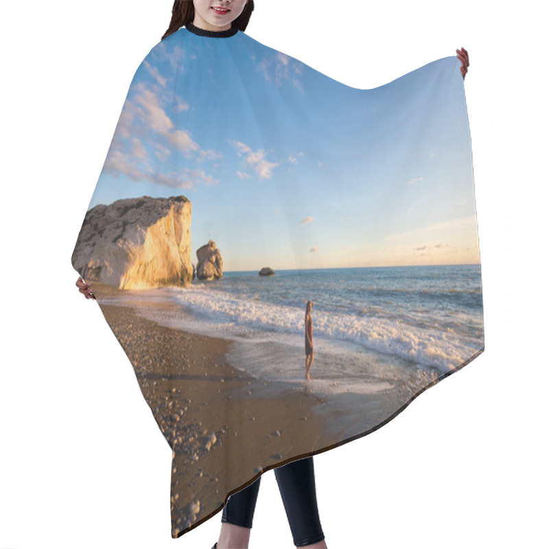 Personality  Young Caucasian Woman Tourist On Beautiful Aphrodite's Rock On Stone Beach During Susnet. Landscape Taken On Cyprus Island. Hair Cutting Cape