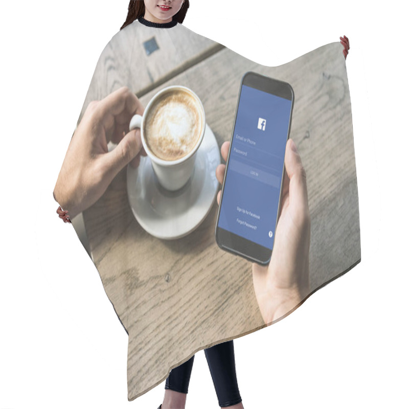 Personality  Cropped Shot Of Man With Cup Of Cappuccino Using Smartphone With Facebook App On Screen Hair Cutting Cape