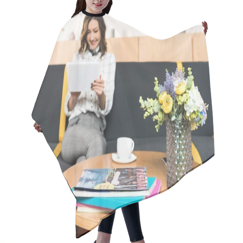 Personality  Happy Young Woman Using Tablet While Sitting On Couch In Cafe With Flowers And Magazines On Table Hair Cutting Cape