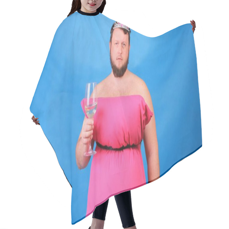 Personality  Funny Bearded Guy In A Pink Dress Made Of Pillows In A Crown With A Glass Of Wine On A Blue Background. Crazy Quarantine. Funny House Cleaning. Fashion 2020. Put On A Pillow. Challenge 2020 Due To Hair Cutting Cape