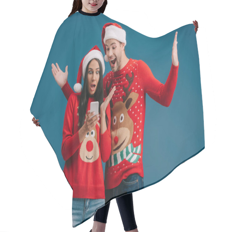 Personality  Excited Couple In Santa Hats And Christmas Sweaters Using Smartphone Isolated On Blue Hair Cutting Cape